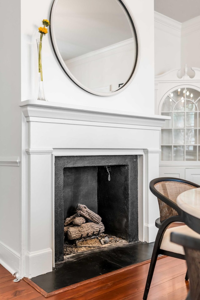 room details with a fireplace with flush hearth, ornamental molding, and wood finished floors