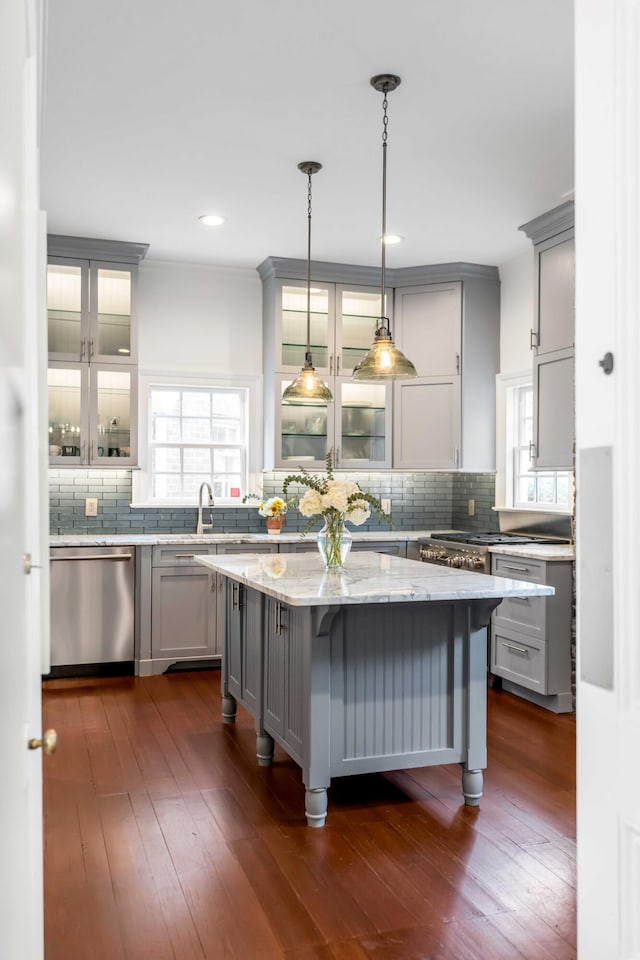 kitchen with light stone counters, dark wood-style flooring, gray cabinets, dishwasher, and tasteful backsplash