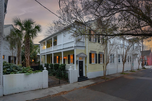 view of front facade featuring a fenced front yard, covered porch, and a balcony