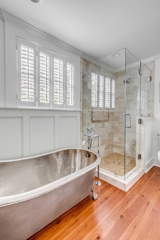 bathroom with a healthy amount of sunlight, a stall shower, wood finished floors, and crown molding