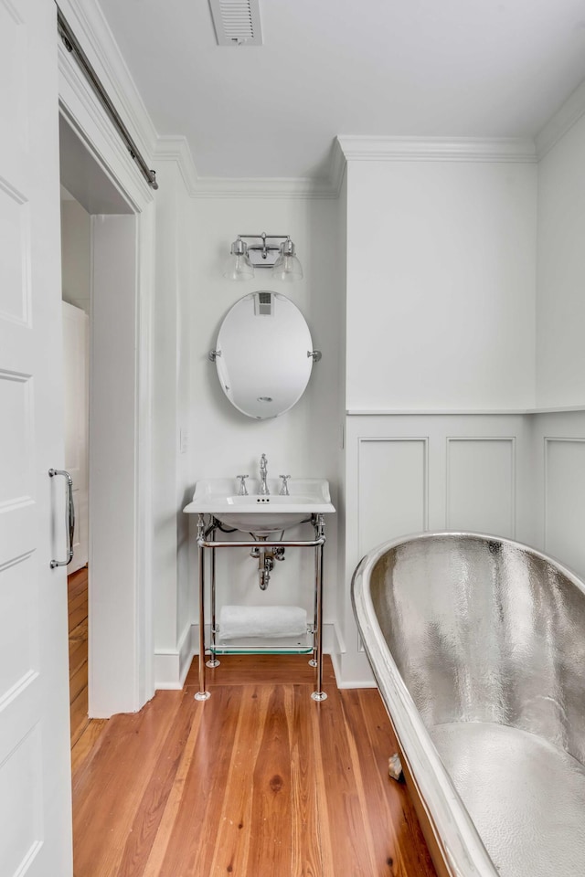 bathroom featuring ornamental molding, visible vents, a sink, and wood finished floors