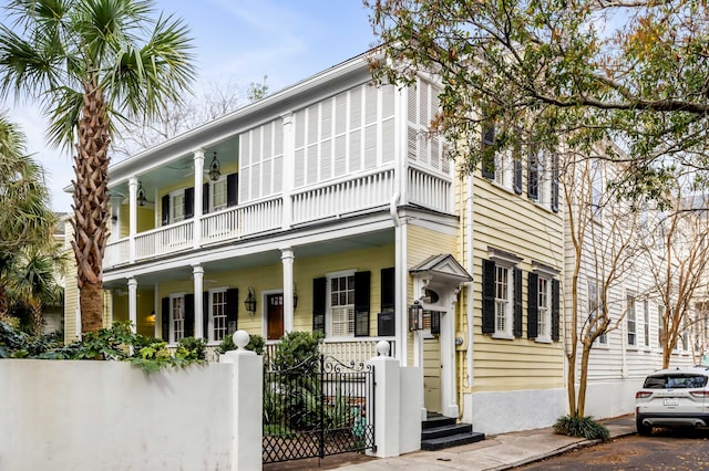 view of front facade featuring a porch, a fenced front yard, and a balcony