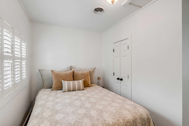 bedroom with a closet, visible vents, and crown molding