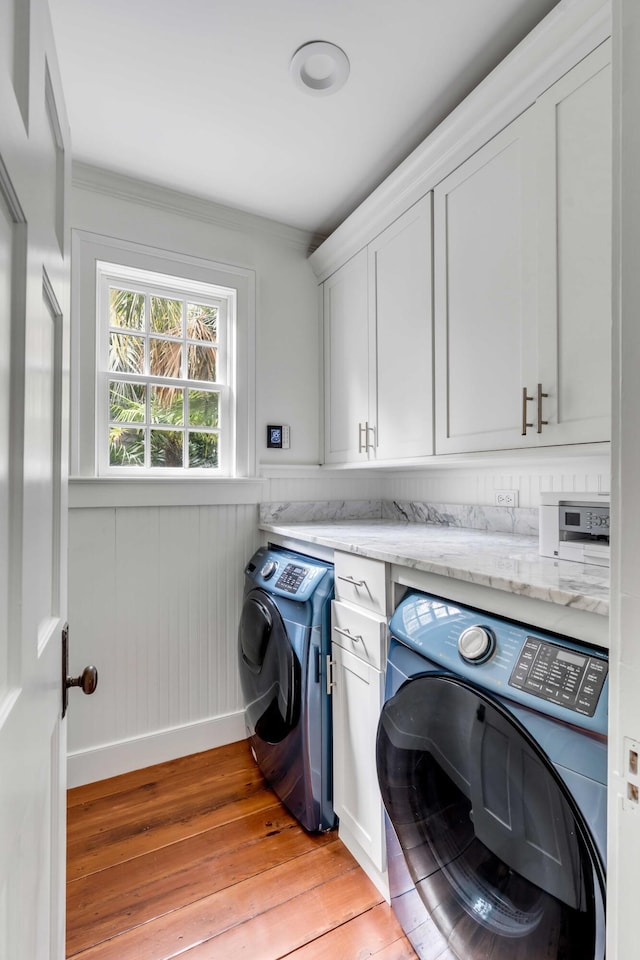 laundry room featuring cabinet space, washer and dryer, light wood-style floors, and a wainscoted wall