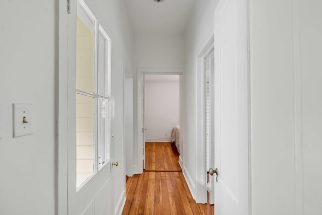 hallway featuring baseboards and light wood finished floors