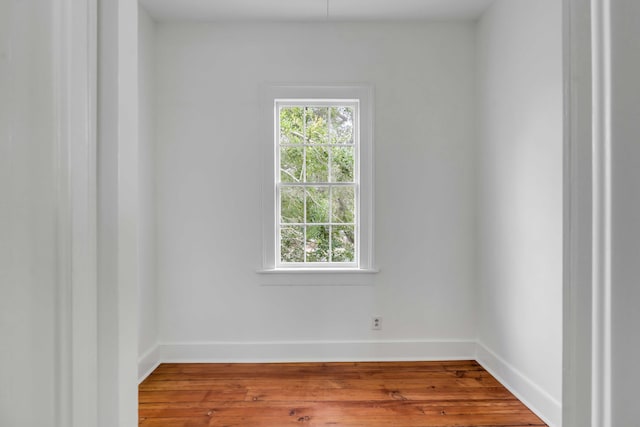 spare room with baseboards and wood finished floors