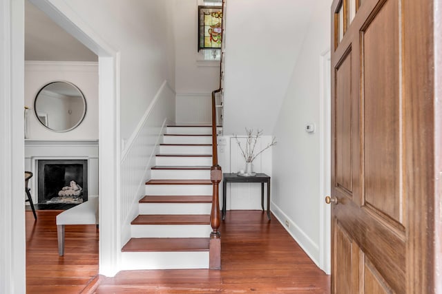 stairway with ornamental molding, a fireplace, baseboards, and wood finished floors