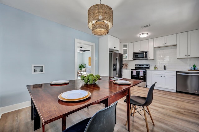 dining room featuring sink, ceiling fan with notable chandelier, and light hardwood / wood-style flooring