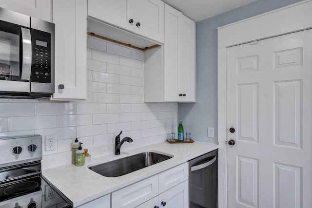 kitchen with white cabinetry, sink, backsplash, light stone counters, and stainless steel appliances