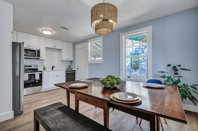 dining room with sink, light hardwood / wood-style flooring, and a chandelier