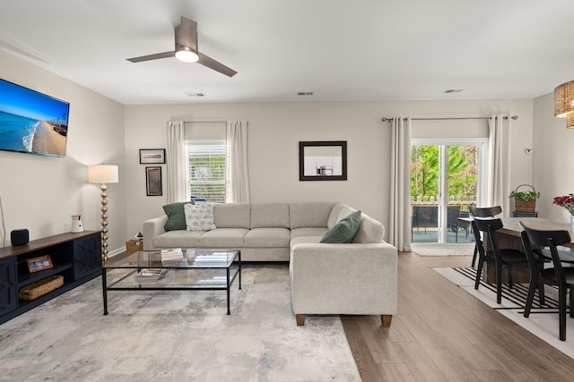 living room with a ceiling fan, wood finished floors, and visible vents