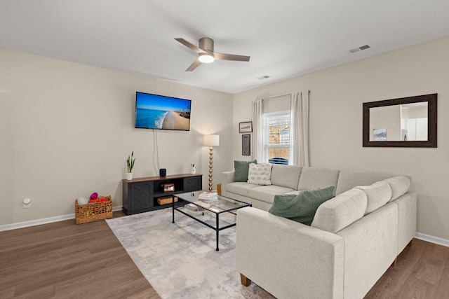 living area featuring visible vents, baseboards, ceiling fan, and wood finished floors