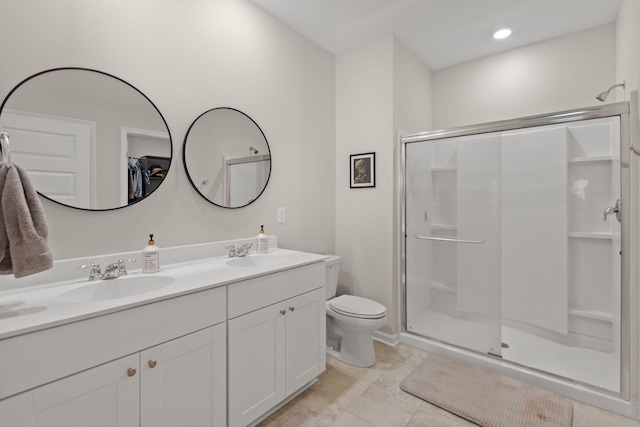 bathroom with double vanity, a shower stall, toilet, and a sink