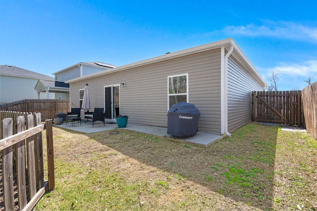 back of property with a patio area, a yard, and a fenced backyard