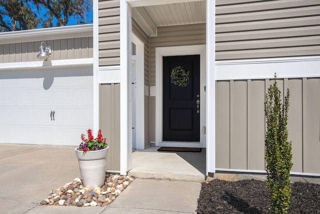 view of exterior entry featuring a garage, board and batten siding, and driveway