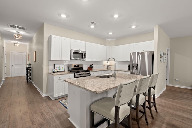 kitchen featuring visible vents, appliances with stainless steel finishes, a breakfast bar, and a sink