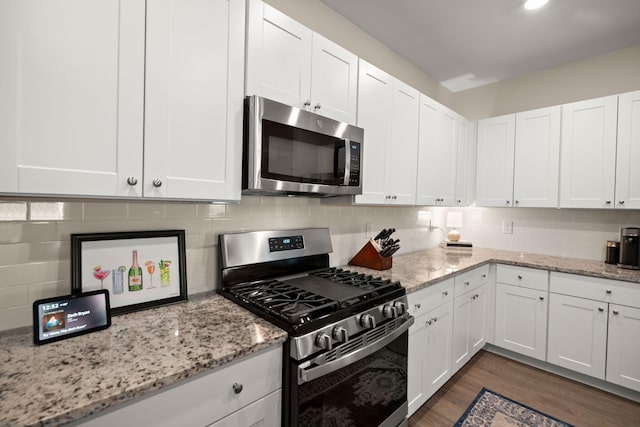 kitchen featuring decorative backsplash, white cabinetry, dark wood-style flooring, and appliances with stainless steel finishes