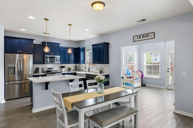 8402 Loggers Run, North Charleston, SC 29420 - kitchen with stainless steel appliances, blue cabinetry, light countertops, decorative backsplash, and a center island