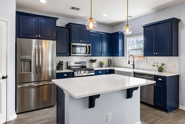 8402 Loggers Run, North Charleston, SC 29420 - kitchen with appliances with stainless steel finishes, blue cabinetry, a breakfast bar, wood finished floors, and recessed lighting