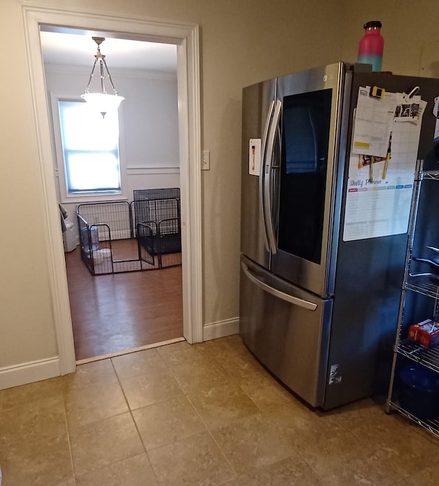 kitchen featuring pendant lighting, crown molding, and stainless steel refrigerator