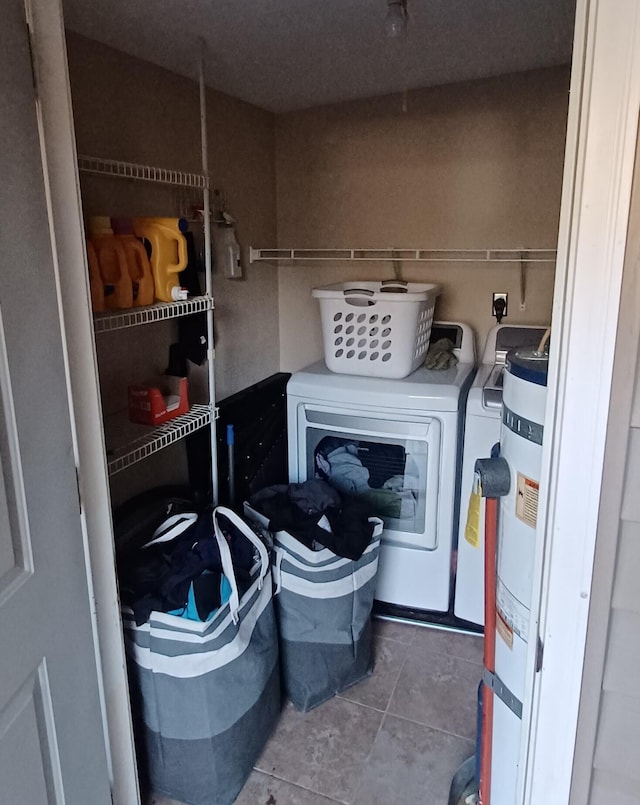 clothes washing area featuring tile patterned flooring, strapped water heater, and washer and dryer