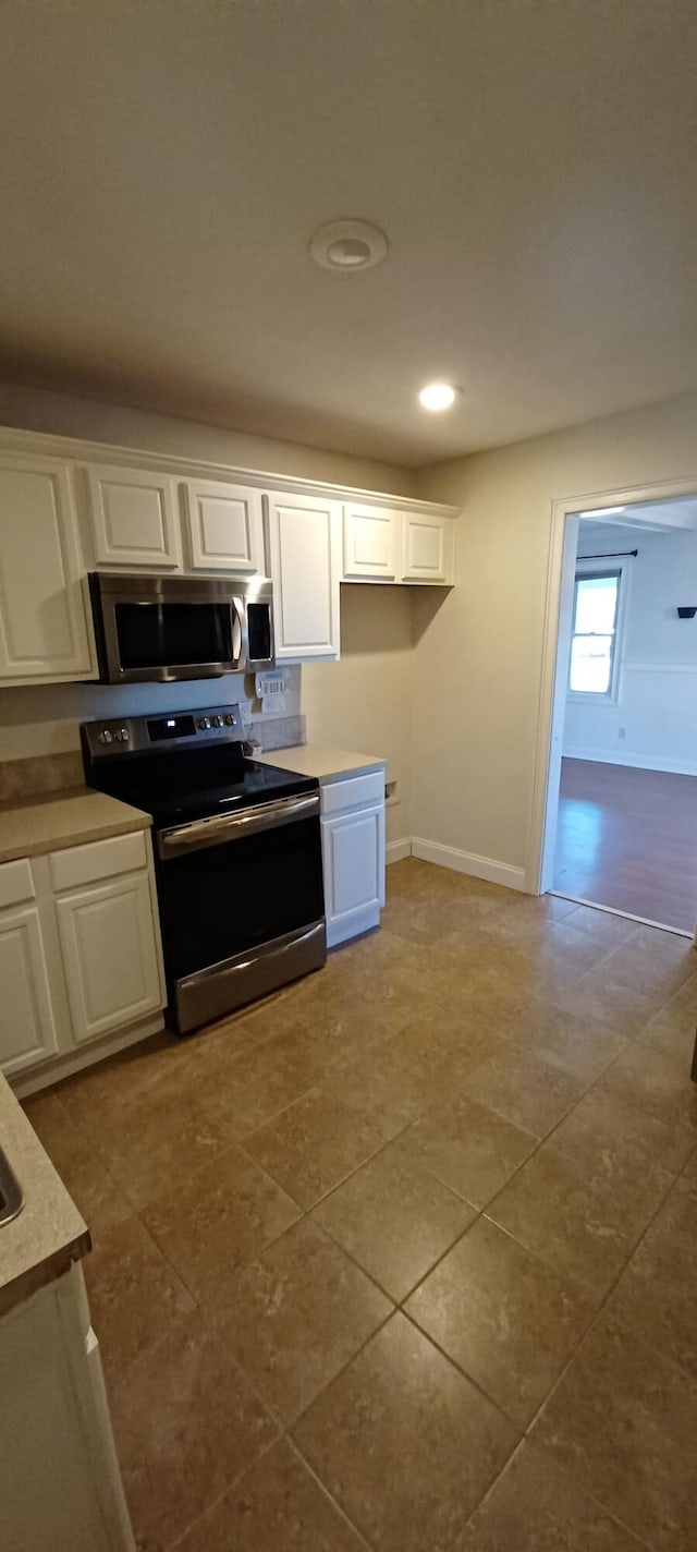 kitchen with white cabinets, appliances with stainless steel finishes, and tile patterned floors