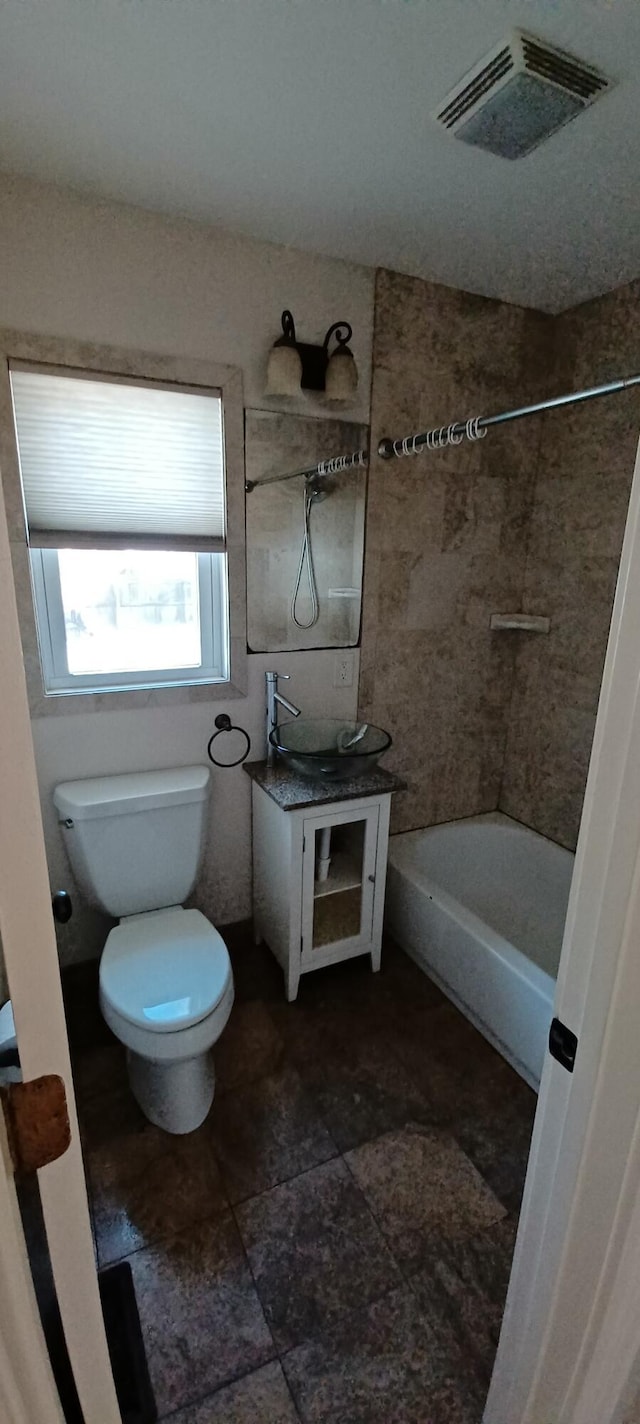 full bathroom featuring tiled shower / bath combo, toilet, and sink