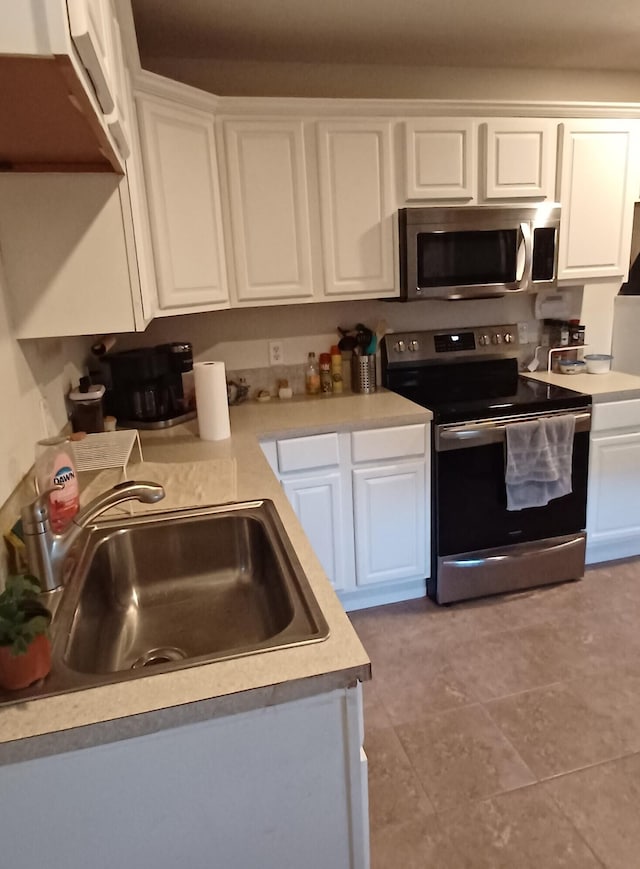 kitchen featuring light tile patterned flooring, appliances with stainless steel finishes, white cabinetry, and sink