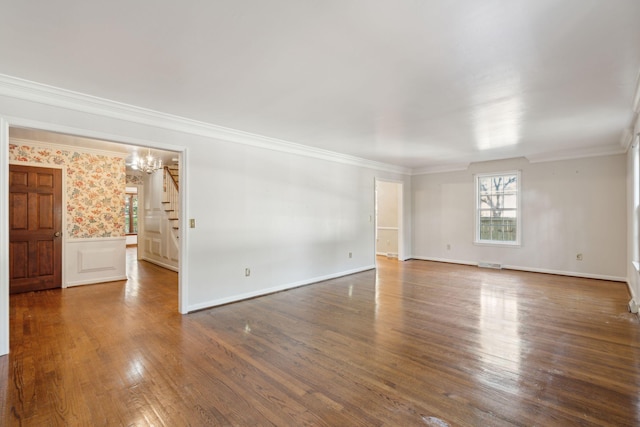 empty room featuring crown molding, dark hardwood / wood-style flooring, and a chandelier