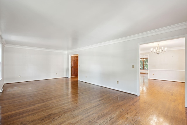 spare room featuring a notable chandelier, dark hardwood / wood-style flooring, and ornamental molding