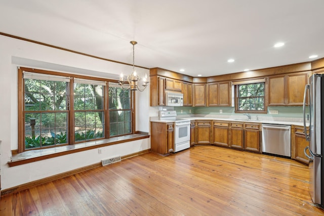 kitchen with a healthy amount of sunlight, light hardwood / wood-style flooring, stainless steel appliances, and decorative light fixtures