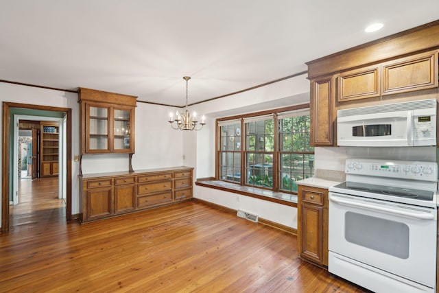 kitchen with ornamental molding, white appliances, a chandelier, hardwood / wood-style floors, and hanging light fixtures