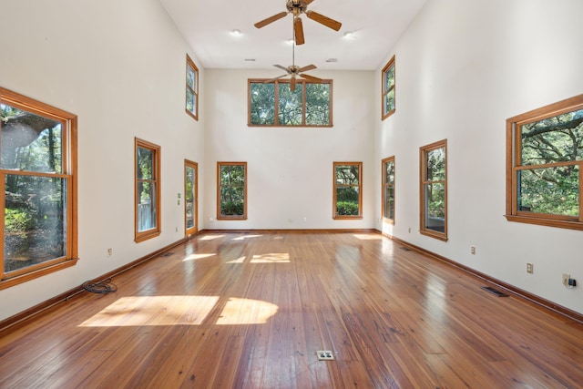 unfurnished living room featuring ceiling fan, hardwood / wood-style floors, and a high ceiling