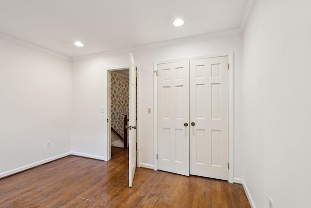 unfurnished bedroom featuring dark hardwood / wood-style flooring, crown molding, and a closet