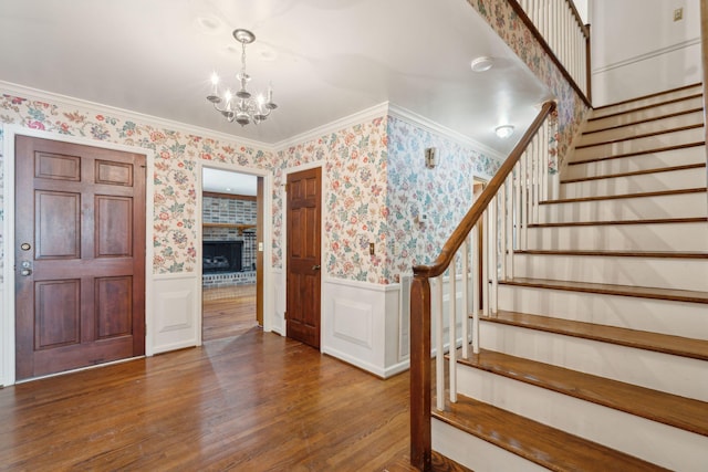 foyer entrance featuring hardwood / wood-style flooring, crown molding, and a chandelier