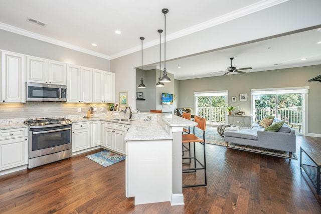 kitchen with a kitchen breakfast bar, a peninsula, visible vents, a sink, and stainless steel appliances