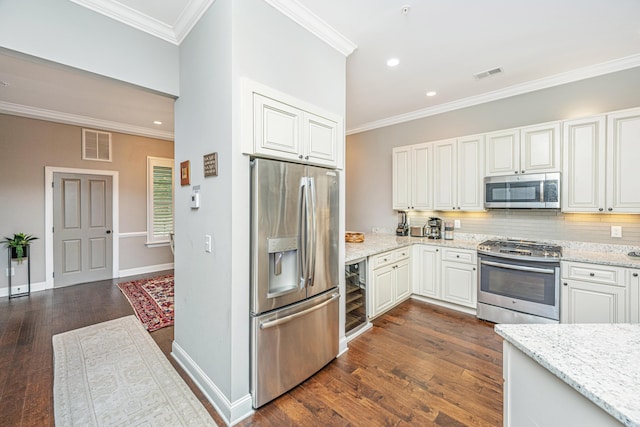 kitchen featuring dark wood-style floors, visible vents, ornamental molding, and appliances with stainless steel finishes