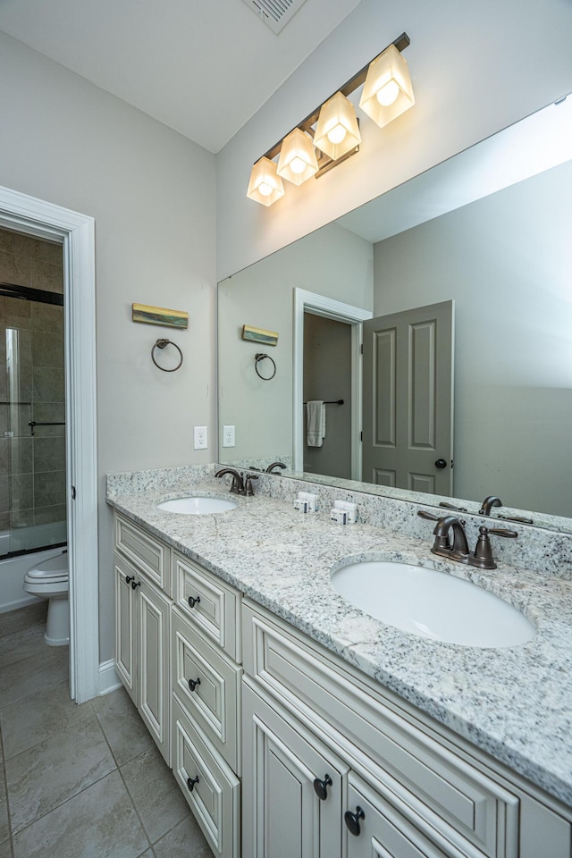 full bathroom with toilet, shower / bath combination with glass door, double vanity, and a sink