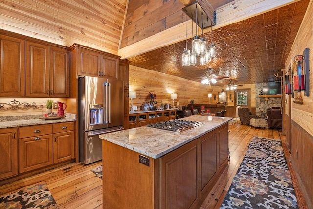 kitchen featuring ceiling fan, a kitchen island, light stone counters, and appliances with stainless steel finishes