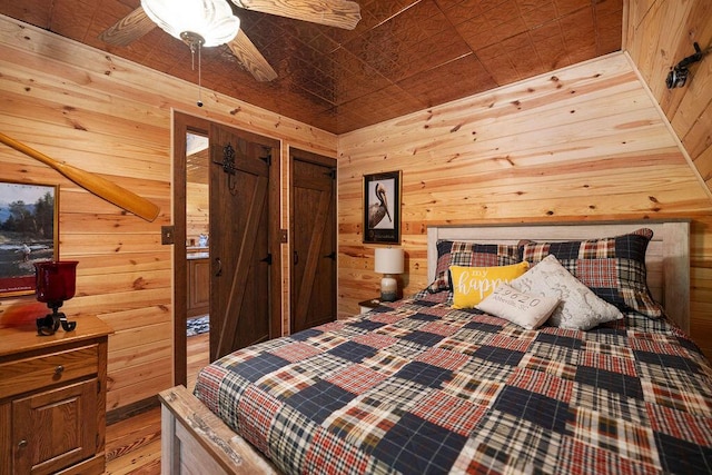 bedroom featuring ceiling fan and wooden walls