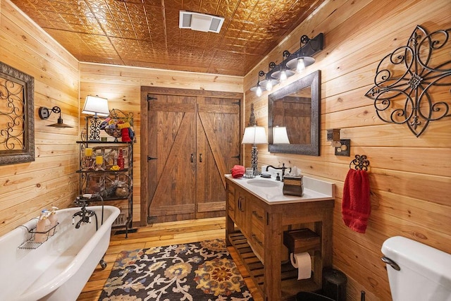 bathroom featuring vanity, toilet, a bathtub, and wooden walls