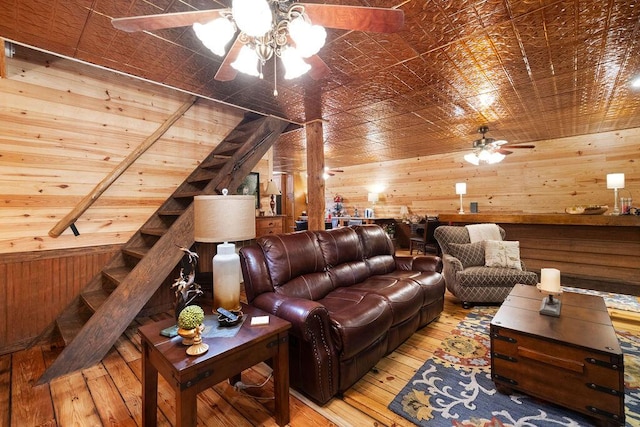 living room featuring wooden walls, ceiling fan, and light wood-type flooring