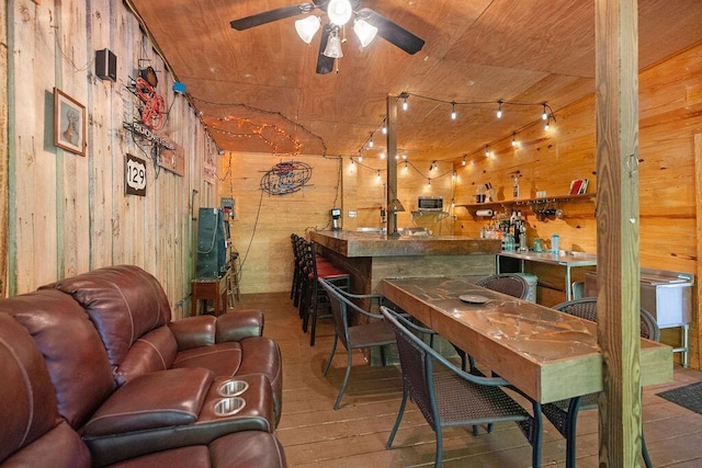 bar featuring ceiling fan, wood-type flooring, wood ceiling, and wooden walls