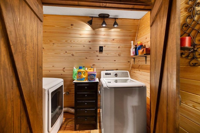 clothes washing area featuring washing machine and clothes dryer and wood walls