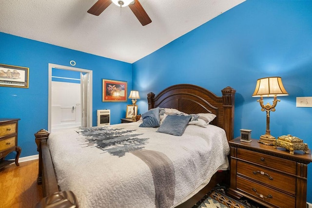 bedroom with hardwood / wood-style floors, ensuite bath, ceiling fan, a textured ceiling, and heating unit