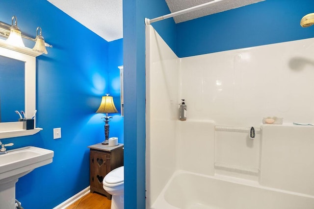 full bathroom featuring shower / bathtub combination, a textured ceiling, sink, wood-type flooring, and toilet