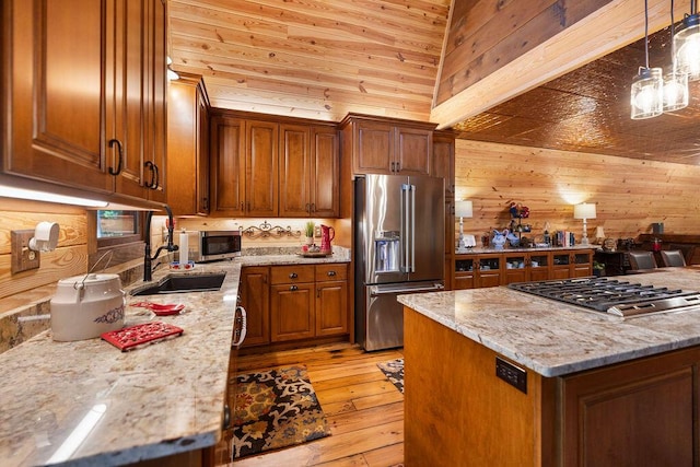 kitchen featuring light stone counters, stainless steel appliances, decorative light fixtures, and custom exhaust hood