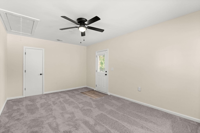 spare room featuring attic access, carpet floors, baseboards, and ceiling fan