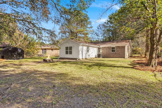 back of property with a yard, central AC, a storage unit, and an outbuilding