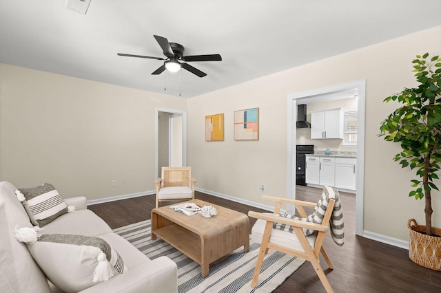 living area featuring baseboards, dark wood finished floors, and ceiling fan